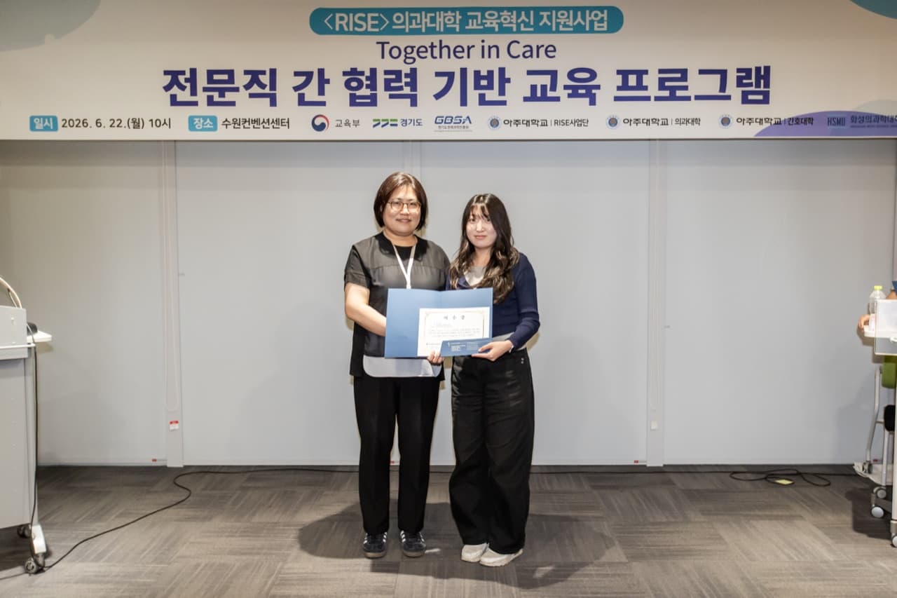 수료식에서 교수가 학생에게 이수증을 수여하는 모습, 'Together in Care 전문직 간 협력 기반 교육 프로그램' 현수막이 배경에 있음