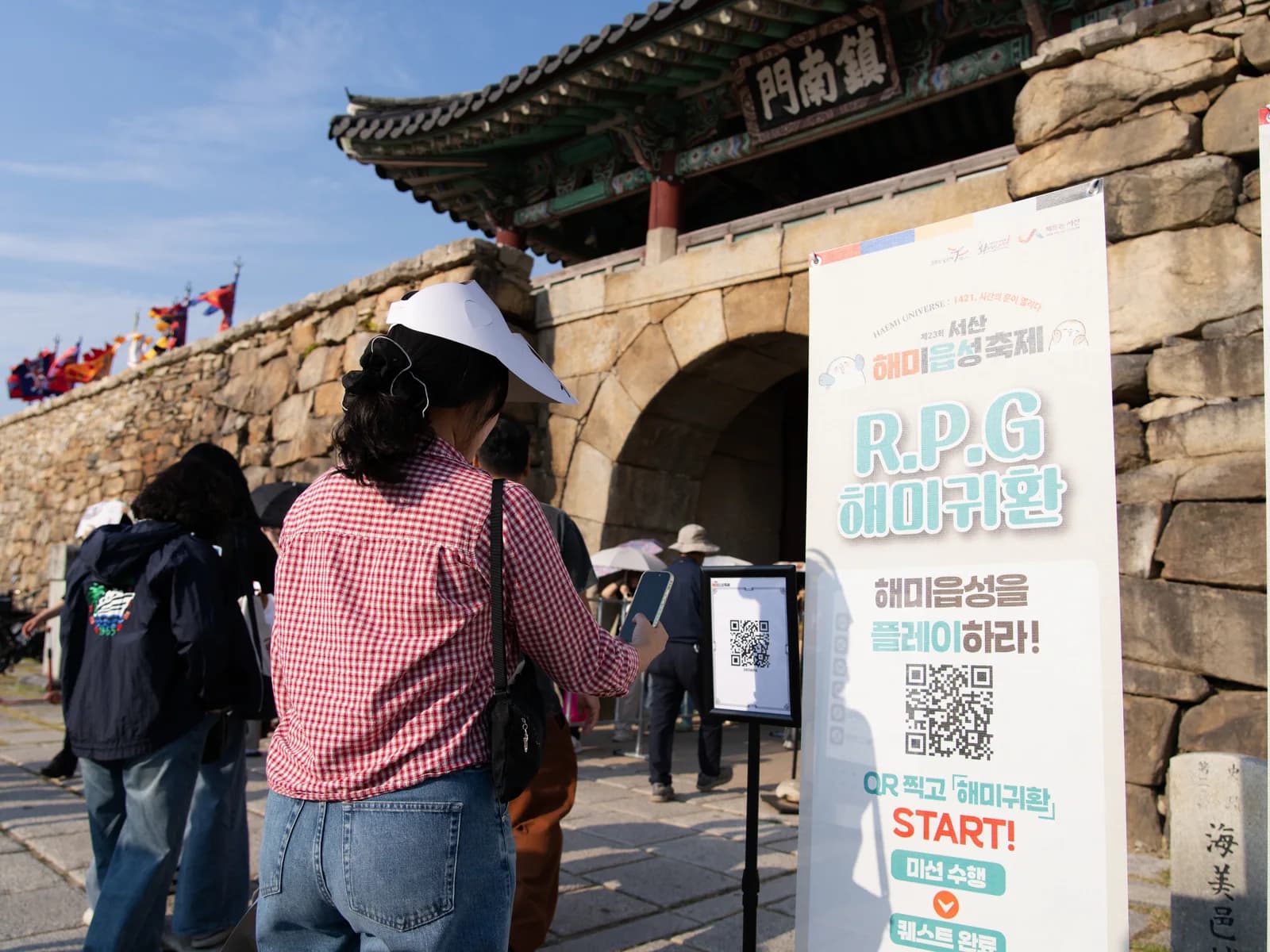 진남문 앞 QR 안내판과 배너 옆을 지나는 방문객