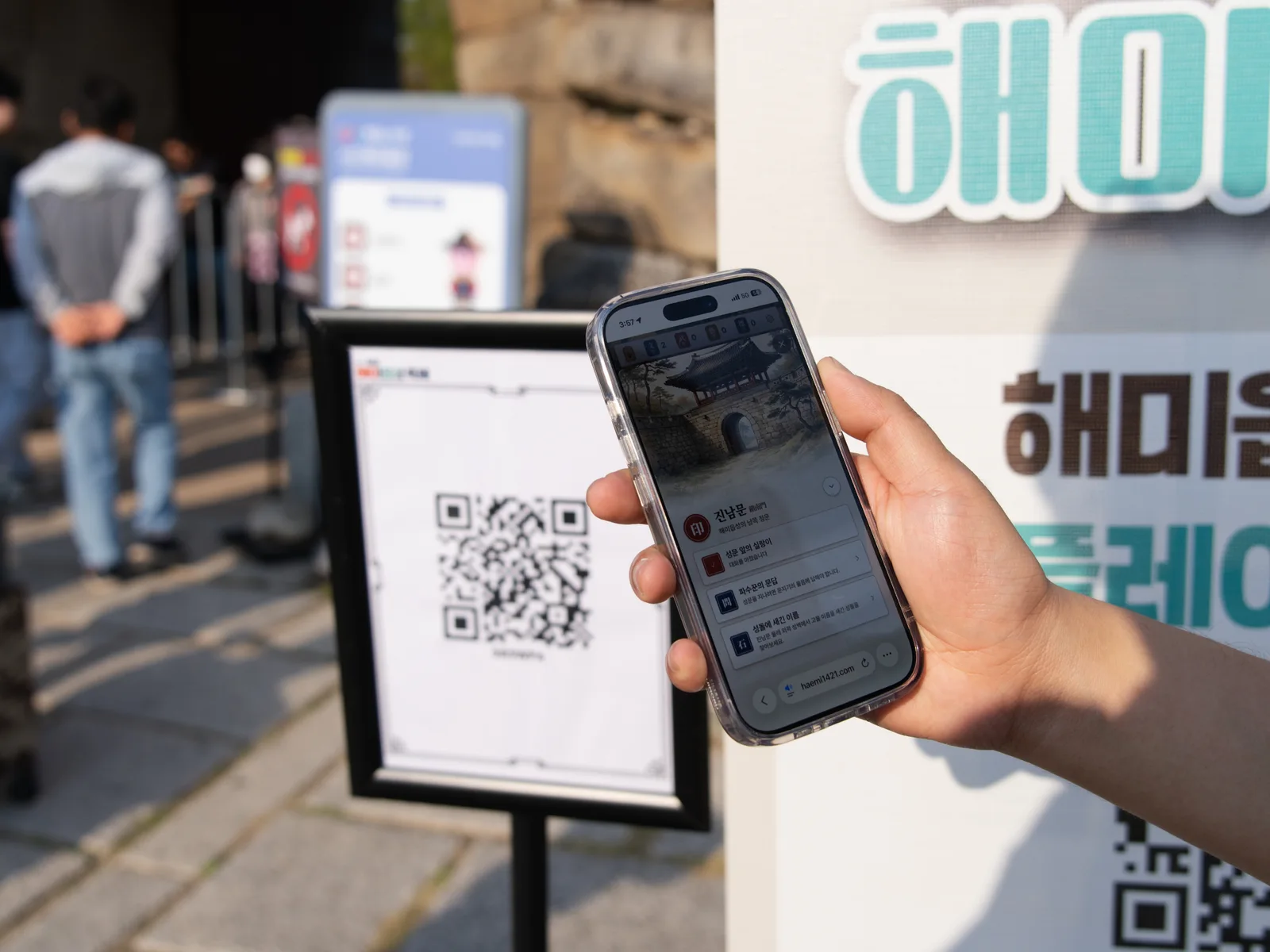QR 안내판 앞 휴대전화 화면과 안내 배너