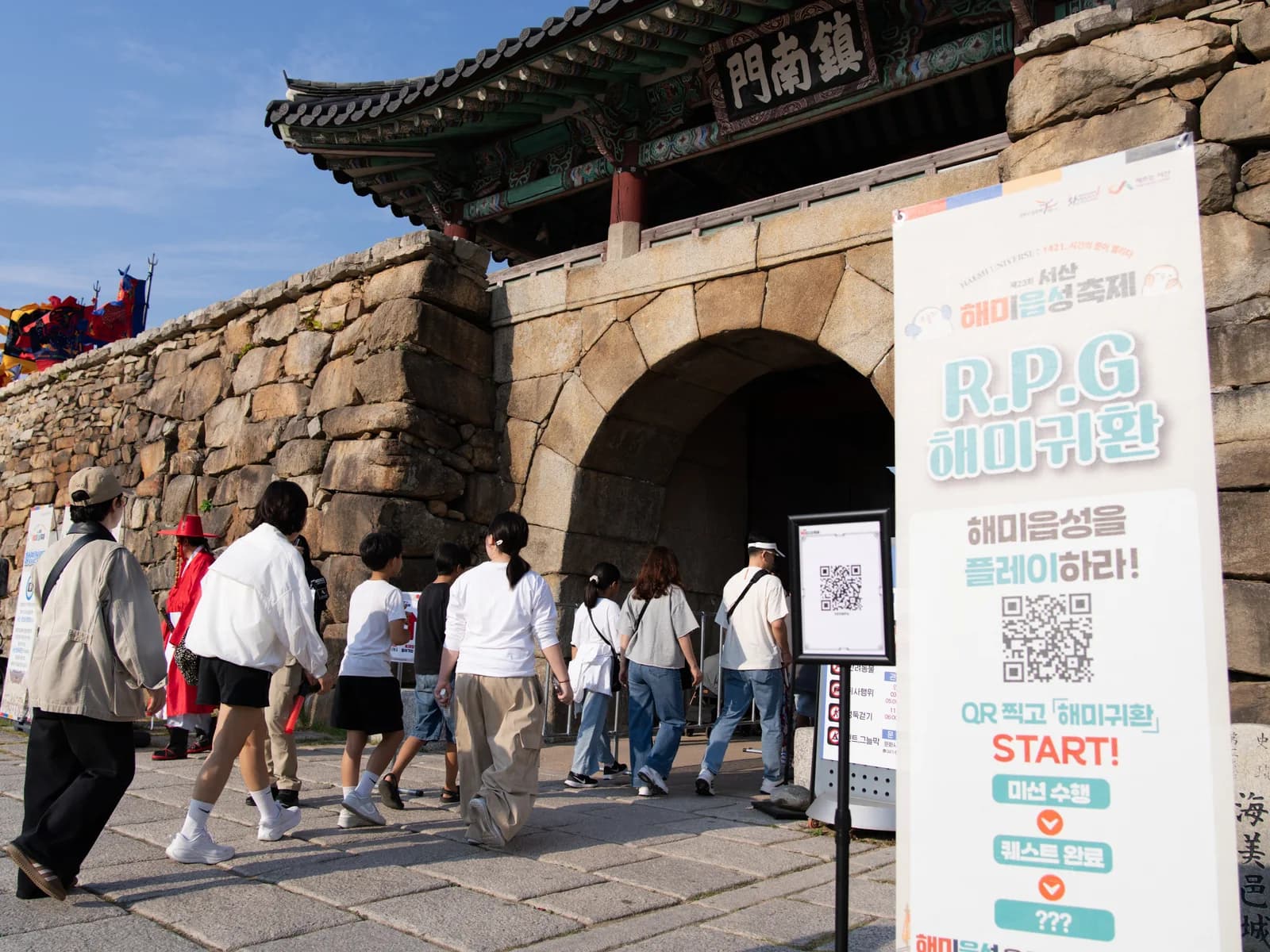 진남문 앞 QR 안내 배너와 안내판 주변을 오가는 방문객