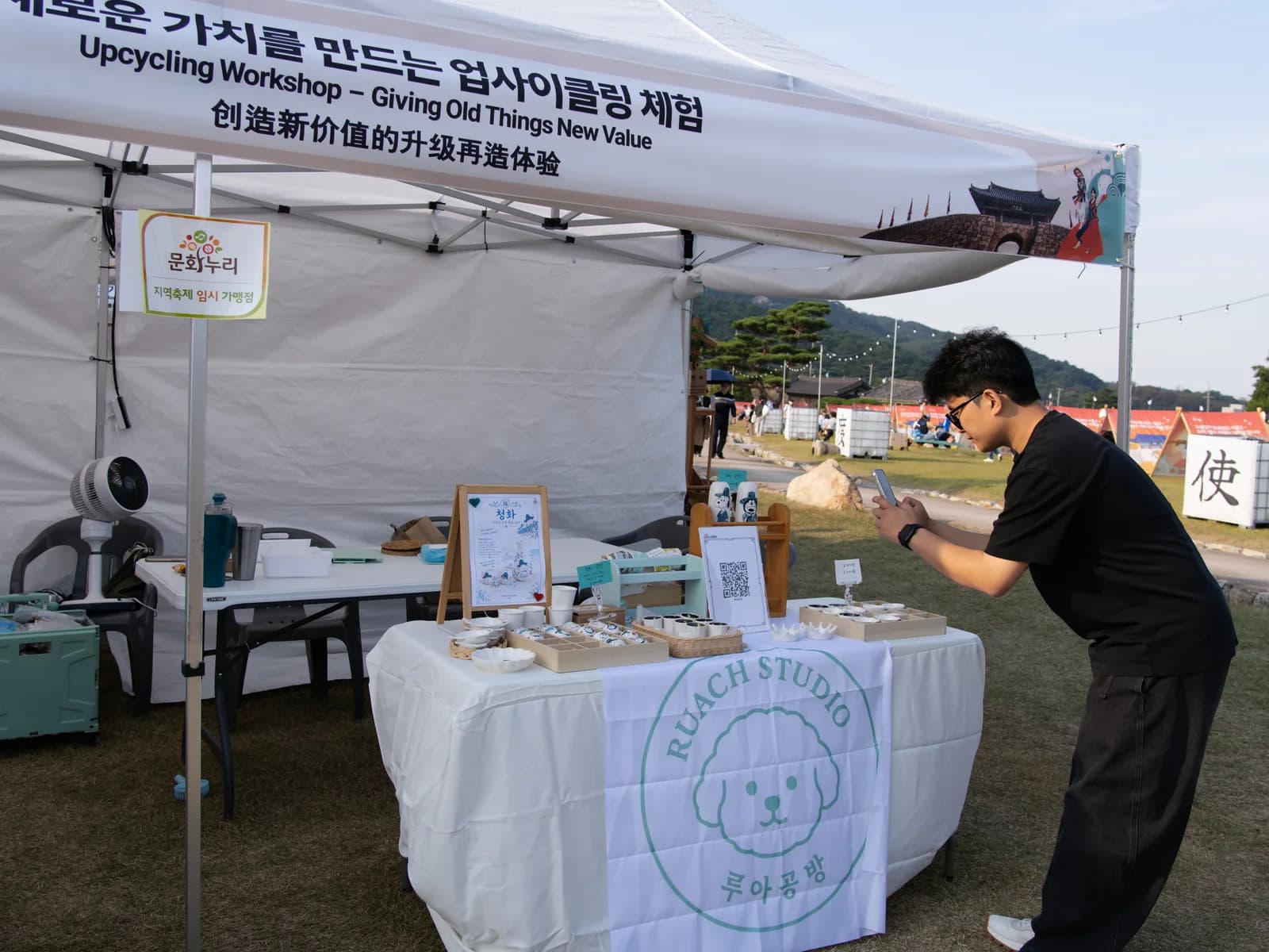 공예 체험 부스 앞에서 휴대전화를 확인하는 모습