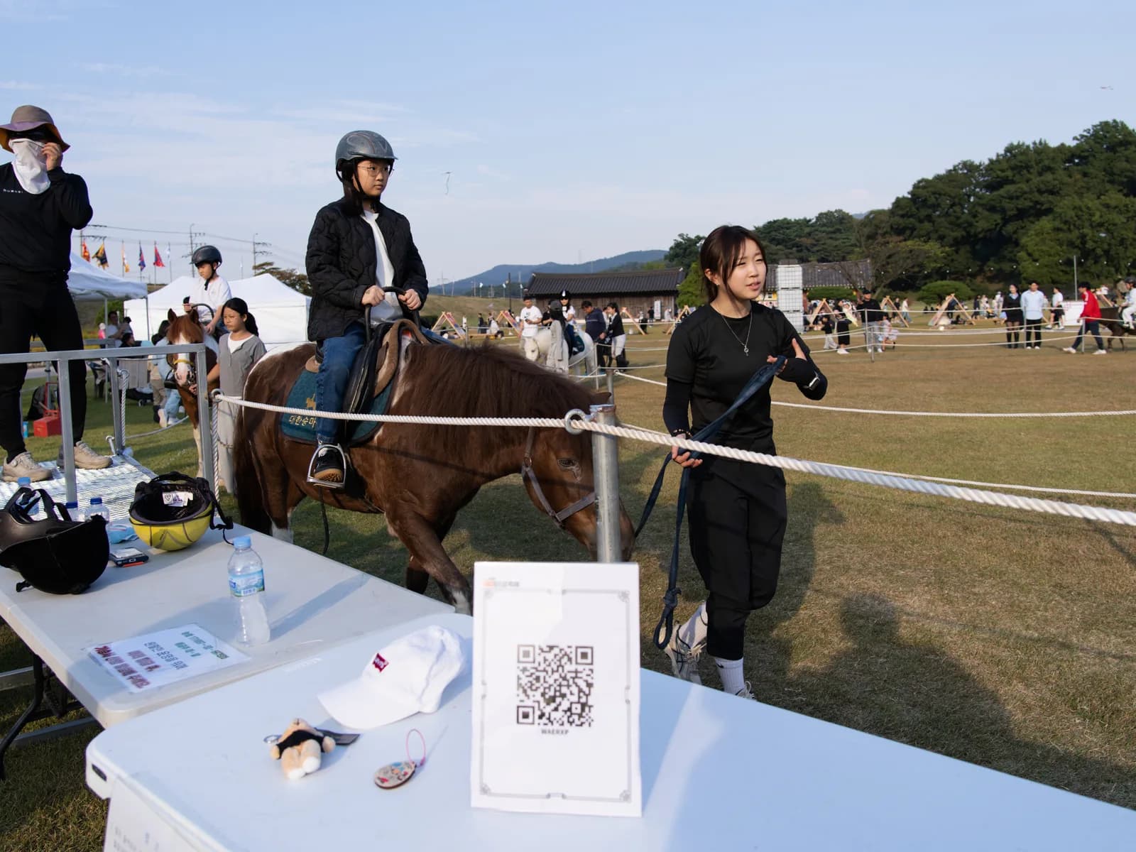 말 체험 공간 앞 테이블의 QR 안내판과 잔디 마당