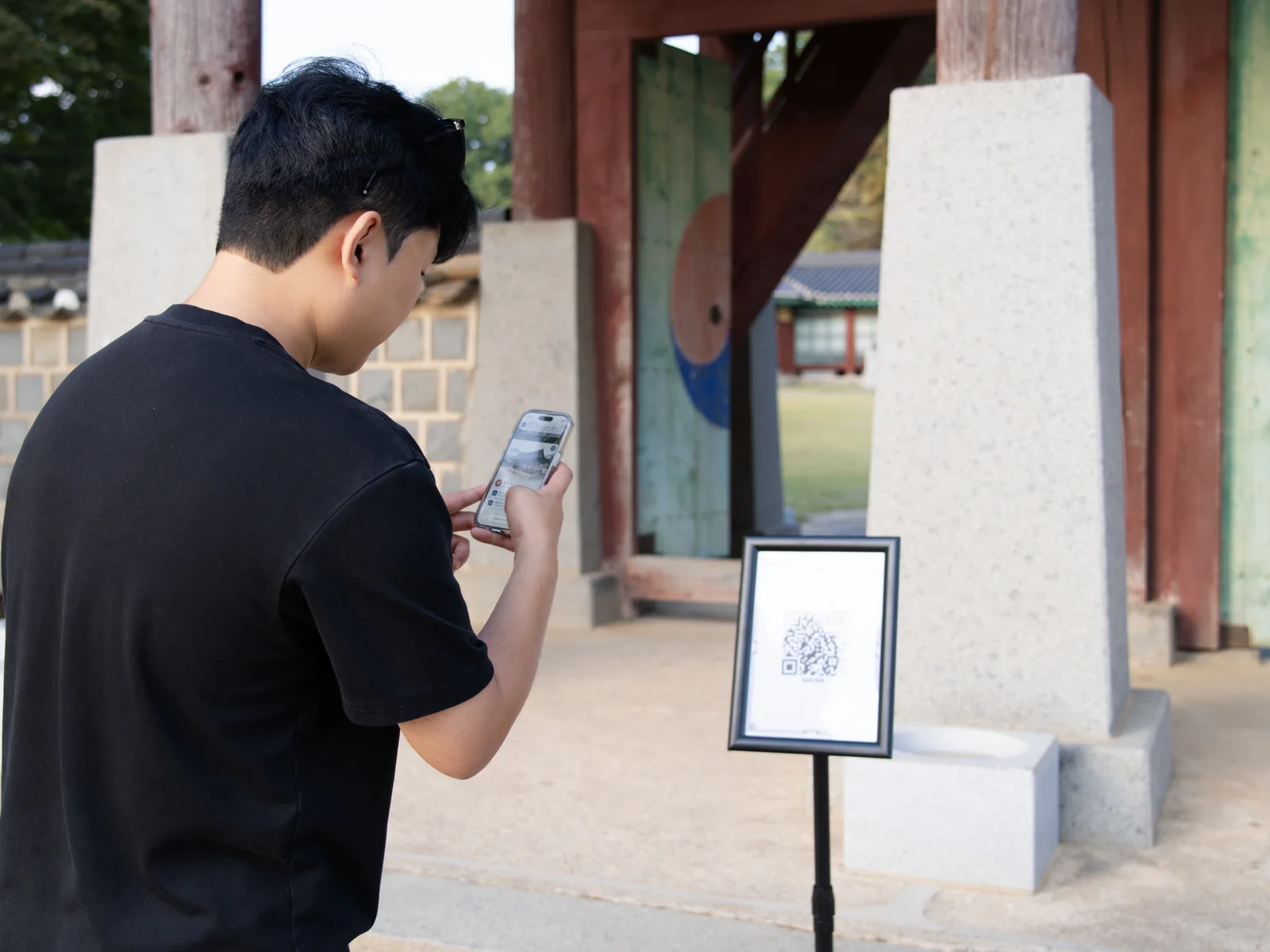 QR 안내판 앞에서 휴대전화를 보는 방문객