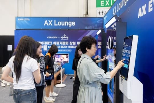 Visitors using kiosks arranged side by side in the AX Lounge